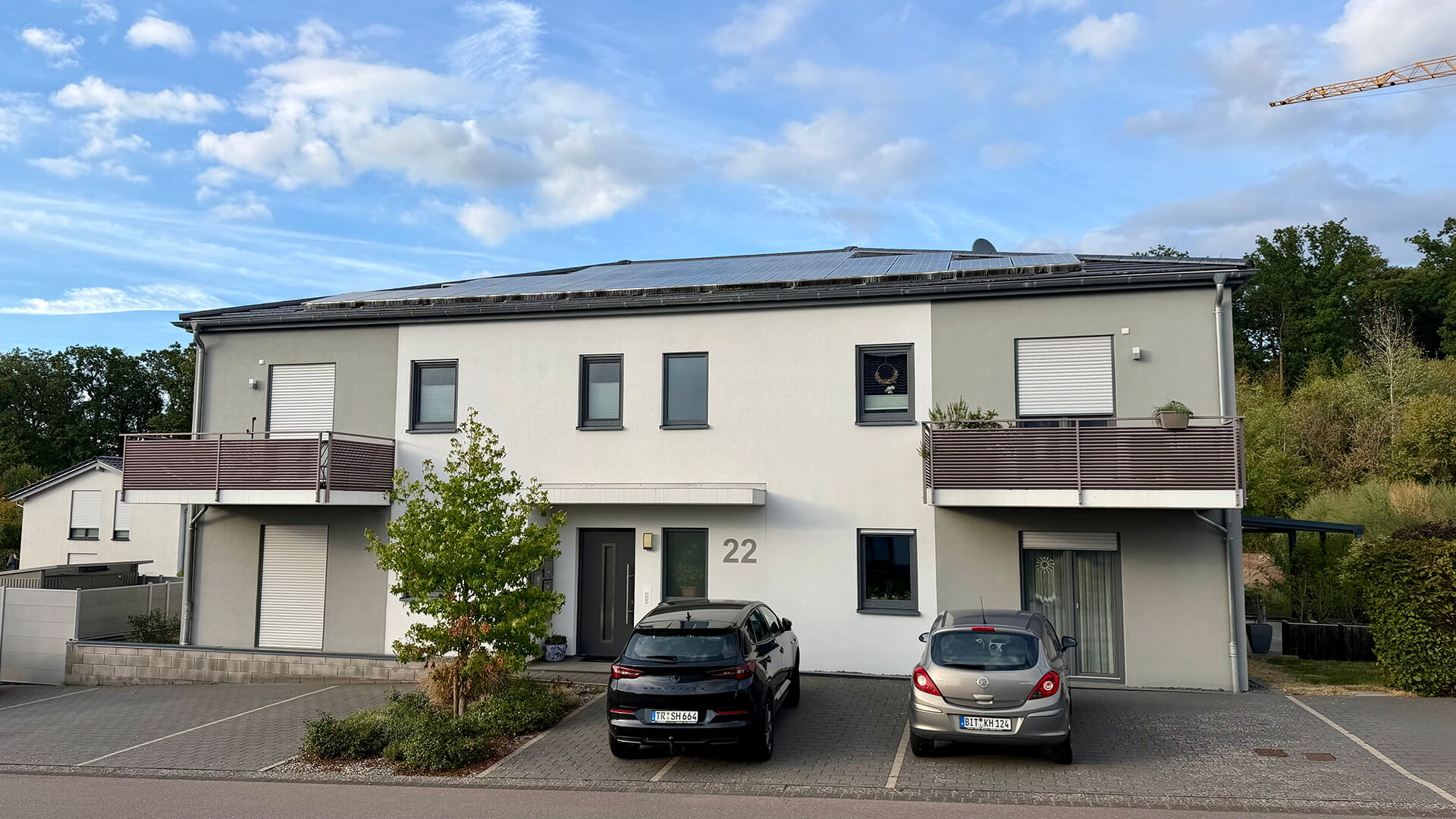 Frontansicht des Wohngebäudes Am Eifelsteig 22 mit heller Fassade, zwei Balkonen und mittigem Hauseingang.